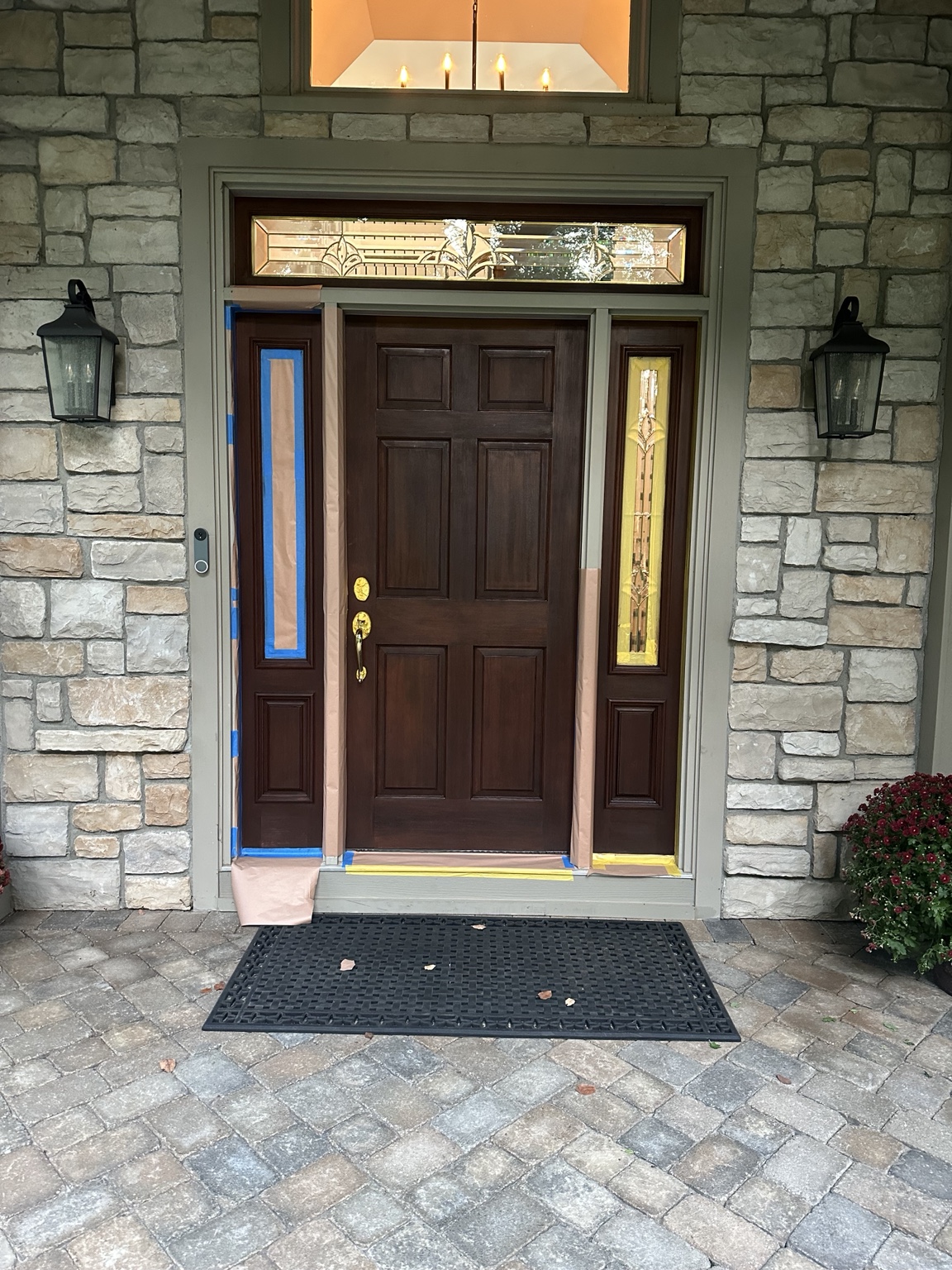 Dark wood entry door with masking around its trim and sidelights