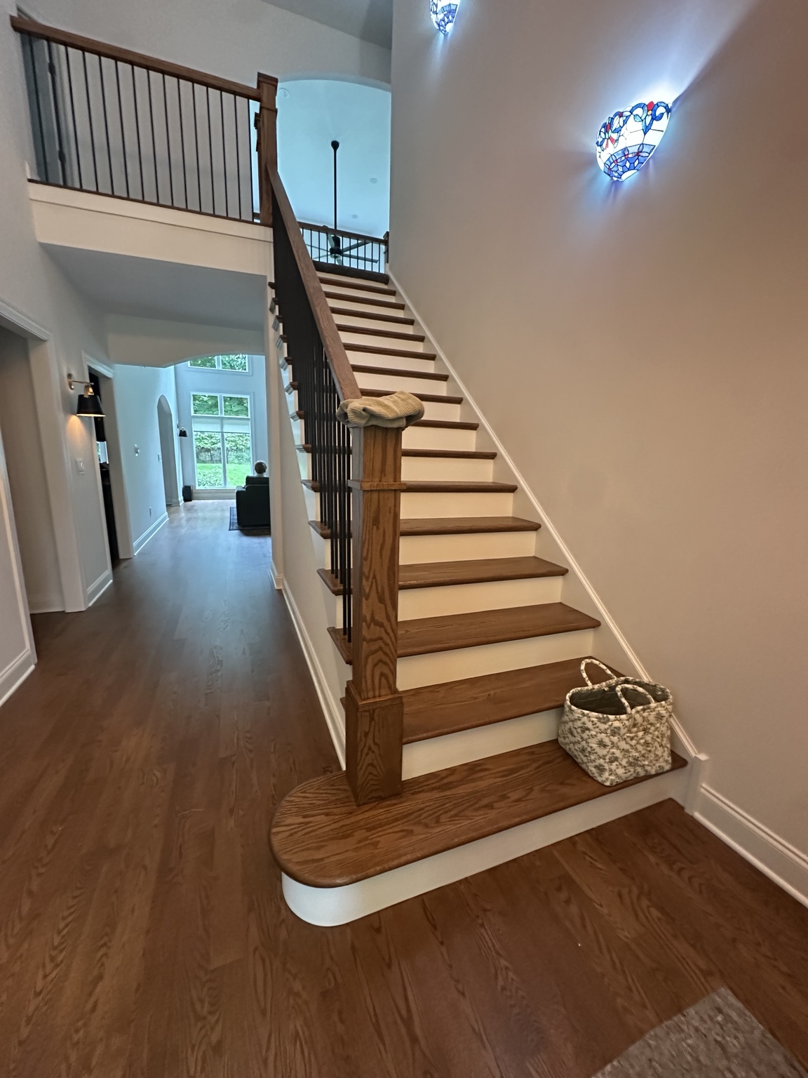 Wood staircase with white risers, dark balusters, and freshly finished surrounding walls