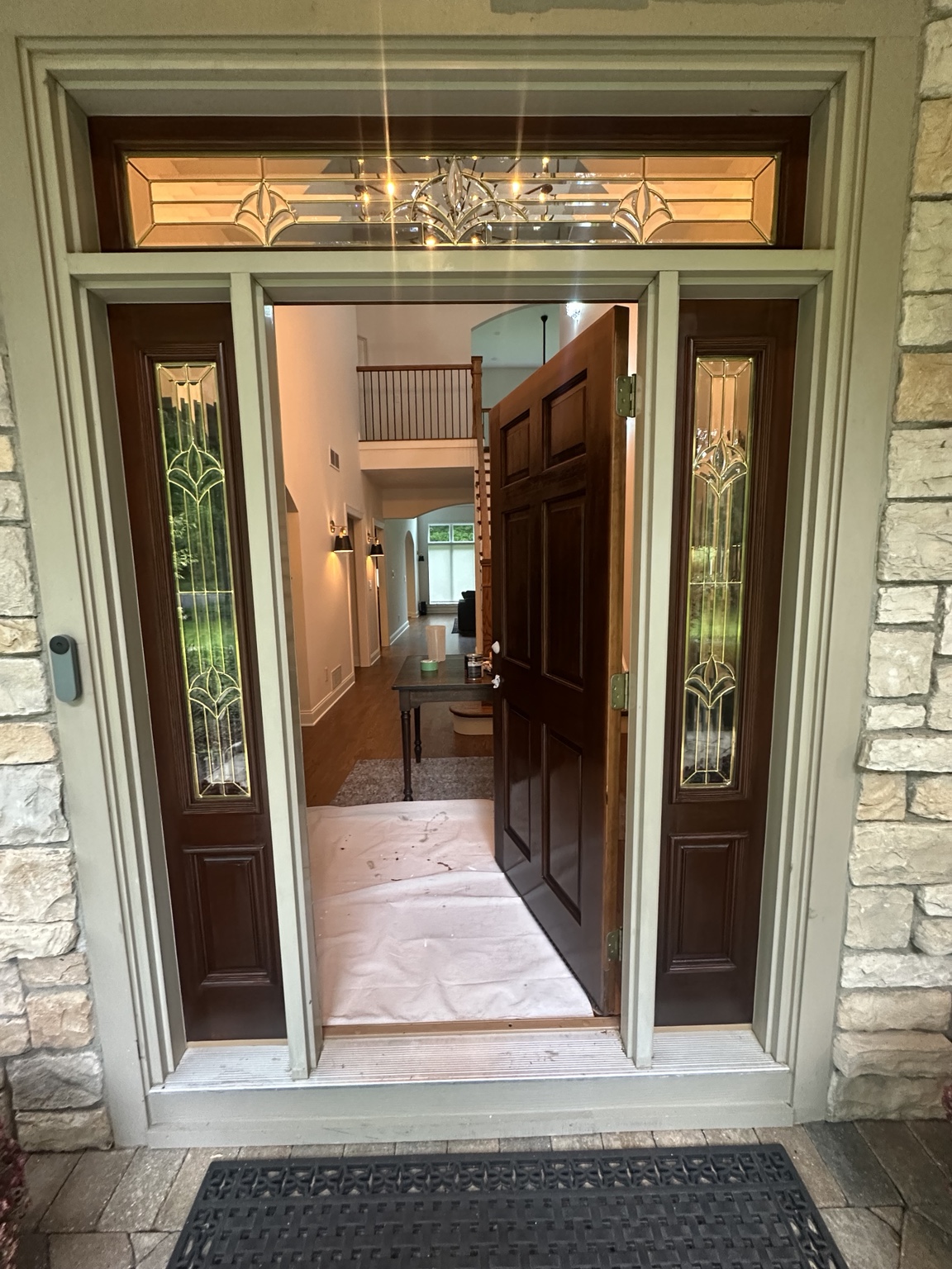 Open wood front door surrounded by decorative glass and painted trim